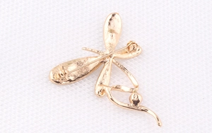 Detailansicht der Rückseite einer goldenen Libelle-Brosche mit Sicherheitsnadel