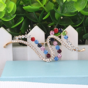Detailed macro view of an elegant curved gold brooch with vibrant colorful rhinestones