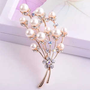Gros plan d'une broche fleur dorée ornée de perles blanches et de cristaux brillants