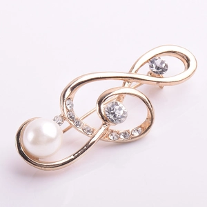 Détail de la broche note de musique dorée avec perle blanche et strass brillants