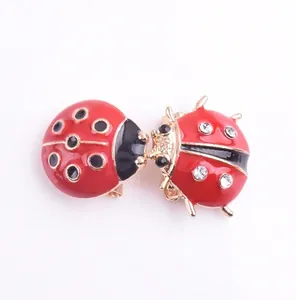Paire de broches coccinelle en émail rouge avec base dorée et strass brillants