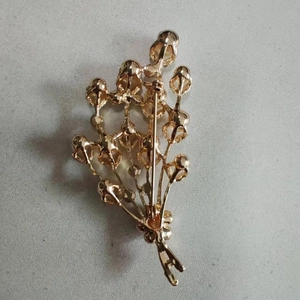 Détail de l'envers d'une broche fleurie montrant l'épingle de sûreté et la base en alliage