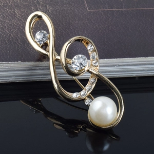 Élégante broche dorée en forme de nœud avec cristaux et perle sur un fond noir brillant
