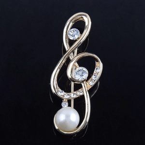 Élégante broche clé de sol dorée ornée de cristaux scintillants et d'une perle blanche
