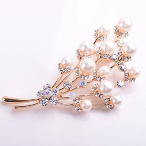 Détail d'une broche branche dorée avec perles blanches et cristaux étincelants