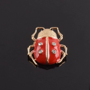 Détail de la broche coccinelle en émail rouge avec cristaux et finition dorée