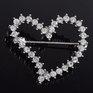 Detail view of rhinestone heart brooch with silver metal base on reflective black surface