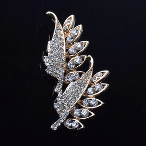 Détail d'une broche feuille dorée sertie de cristaux brillants sur fond noir