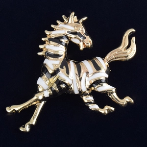 Detailed macro view of zebra brooch with gold metal trim and black white enamel stripes