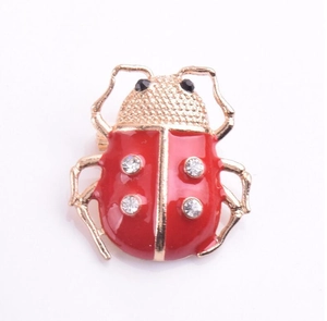 Détail de la broche coccinelle mignonne avec ailes en émail rouge et strass étincelants