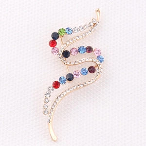 Detailed view of S-shaped golden brooch with colorful inlaid rhinestones and pin clasp