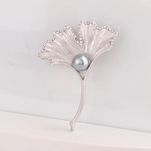 Detailed view of silver ginkgo leaf brooch with brushed texture and grey pearl