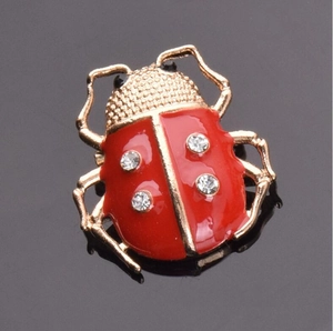 Vue détaillée de la broche coccinelle en émail rouge avec des strass étincelants