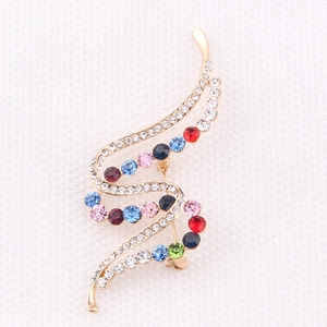 Close-up of S-shaped colorful crystal brooch with gold base and multicolor rhinestones