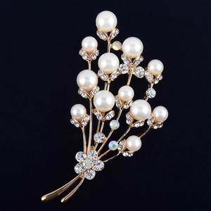 Gros plan d'une broche fleur dorée avec des strass en cristal et des perles blanches élégantes