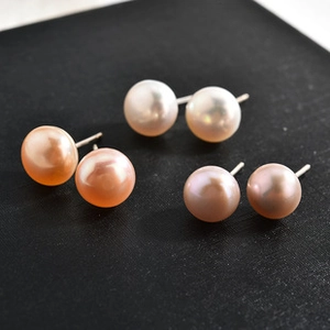 Close-up of pearl earrings in white, lavender, and pink orange with metallic posts