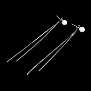 Close-up of elegant long tassel earrings featuring round white pearls and silver bars
