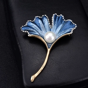 Detailed macro of ginkgo leaf brooch with blue enamel, white pearls and sparkling rhinestones