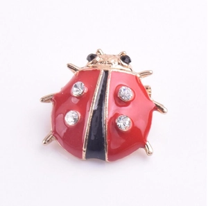 Détail de la broche coccinelle en émail rouge et noir avec base dorée et strass brillants