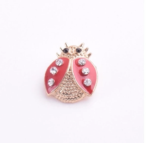 Vue détaillée d'une broche coccinelle en émail rouge et strass blancs brillants