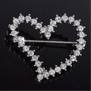 Elegant silver heart-shaped brooch with clear rhinestones on a black reflective surface