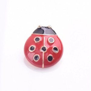 Détail de la broche coccinelle en émail rouge et noir avec finition dorée