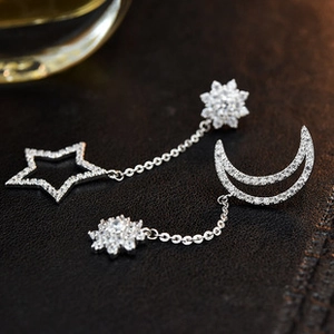 Macro shot of silver bow earrings with zircon stars and moon pendants on leather