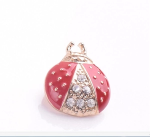 Détail d'une adorable broche coccinelle en émail rouge ornée de strass en cristal brillants