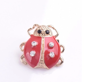 Détail de la broche coccinelle avec émail rouge et strass blancs sur métal doré