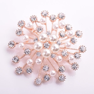 Vue détaillée d'une broche fleur or rose avec perles et strass sur fond blanc épuré