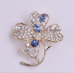 Gros plan détaillé d'une broche trèfle dorée ornée de cristaux bleus et de strass brillants