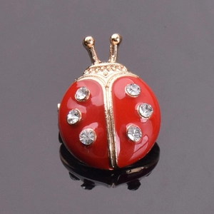 Détail de la broche coccinelle en émail rouge avec cristaux sur surface noire
