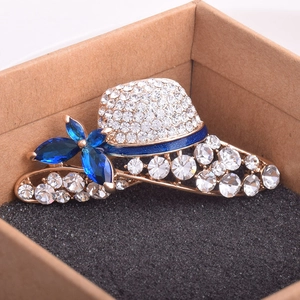 Detail view of crystal hat brooch with blue marquis gems and gold base on black sponge