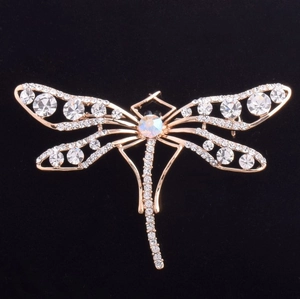 Détail de la broche libellule plaquée or avec cristaux sur fond de velours noir