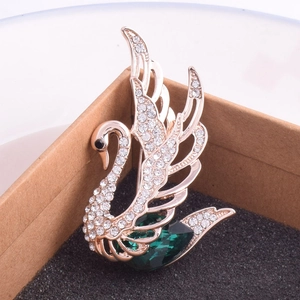 Détail d'une broche cygne en cristal avec pierre précieuse verte dans un coffret à bijoux