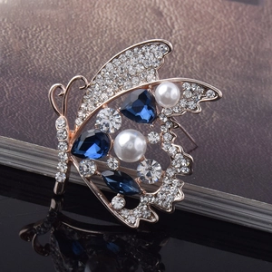 Détails d'une broche papillon en cristal avec pierres bleues, perles et placage or rose
