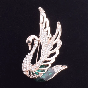 Détail de la broche cygne avec finition or rose et un grand cristal de couleur verte