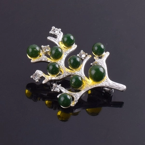Détail d'une broche branche argentée avec des perles vertes et des cristaux brillants