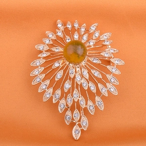 Macro shot of sunburst brooch with yellow amber stone and crystals on orange silk