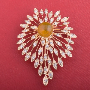 Macro detail of golden flower brooch with yellow gemstone and clear crystal petals