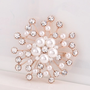 Macro d'une broche en or rose avec perles crème et cristaux brillants étincelants