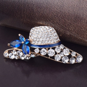 Elegant gold hat brooch with sparkling crystals and navy blue flower accents on leather
