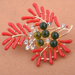 Détail de la broche corail avec perles vertes et strass sur base dorée