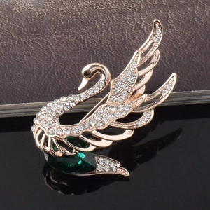 Détail de la broche cygne en cristal avec plaquage or rose et pierre verte en goutte