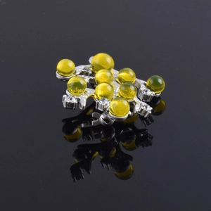 Détail d'une broche branche argentée avec perles d'ambre jaune et cristaux brillants