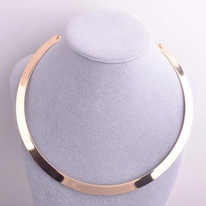 Close-up of polished light gold wide metal choker necklace on a grey velvet mannequin