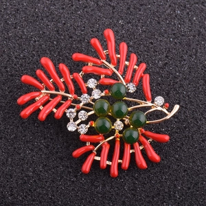 Vue détaillée d'une broche avec branches de corail rouge et perles vertes sur or