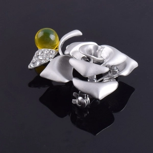 Macro detail of silver rose flower brooch with blue amber bead and sparkling crystals