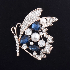 Détails d'une broche papillon en or rose avec cristaux bleu foncé et perles blanches