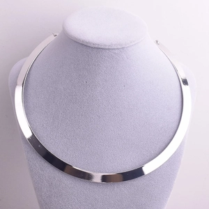 Detail view of a minimalist silver alloy choker necklace on a grey velvet jewelry stand